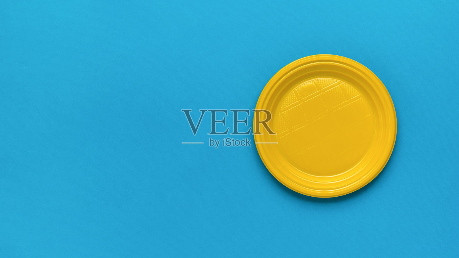 蓝色背景的黄色塑料板。放文本的地方。平的。照片摄影图片