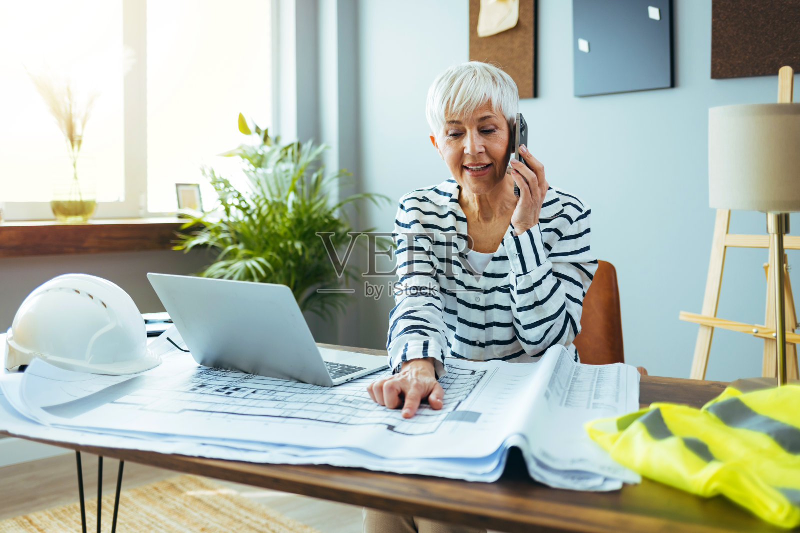 成熟的女商人在办公室打电话。照片摄影图片