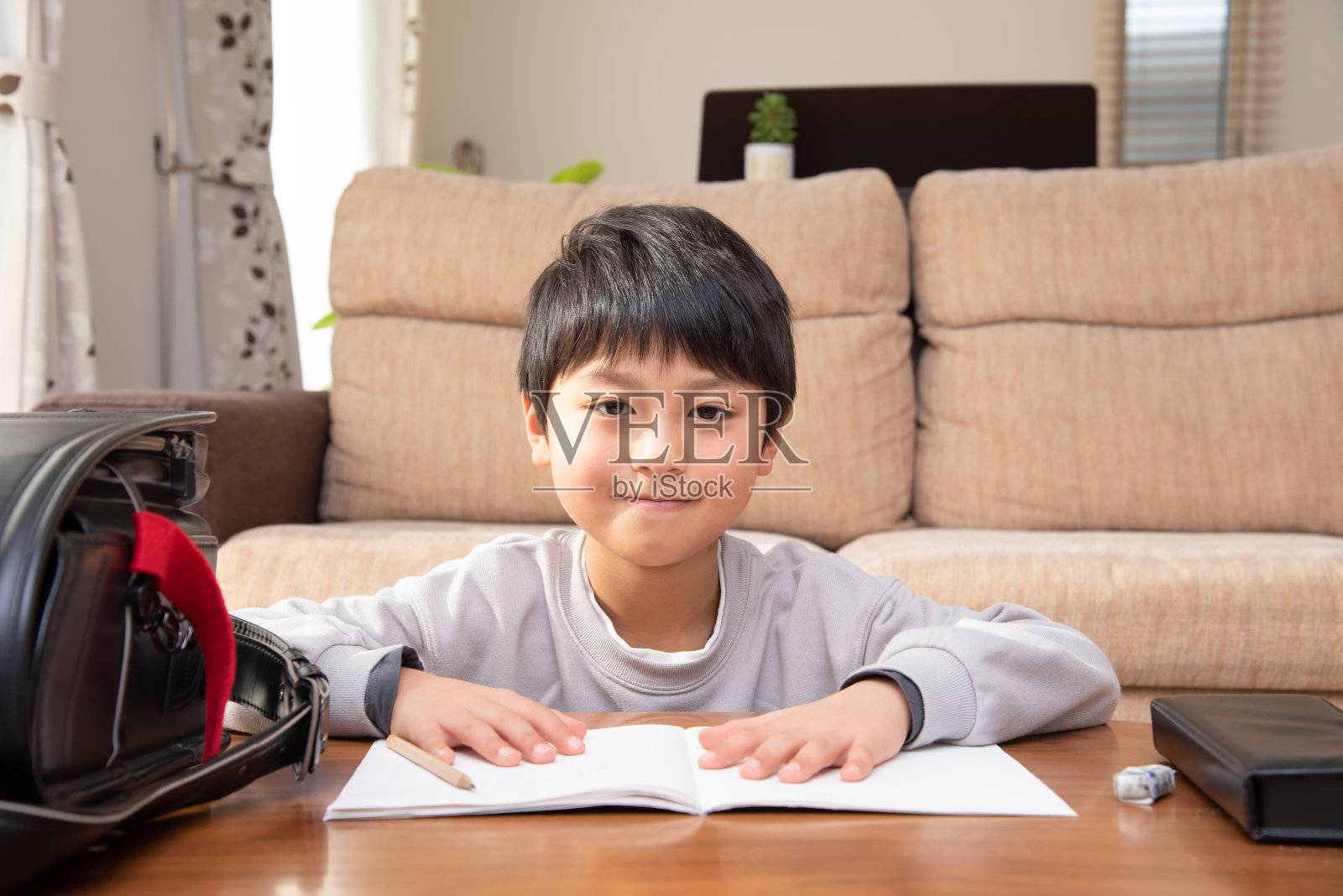 日本男孩放学回家，在客厅里做作业照片摄影图片