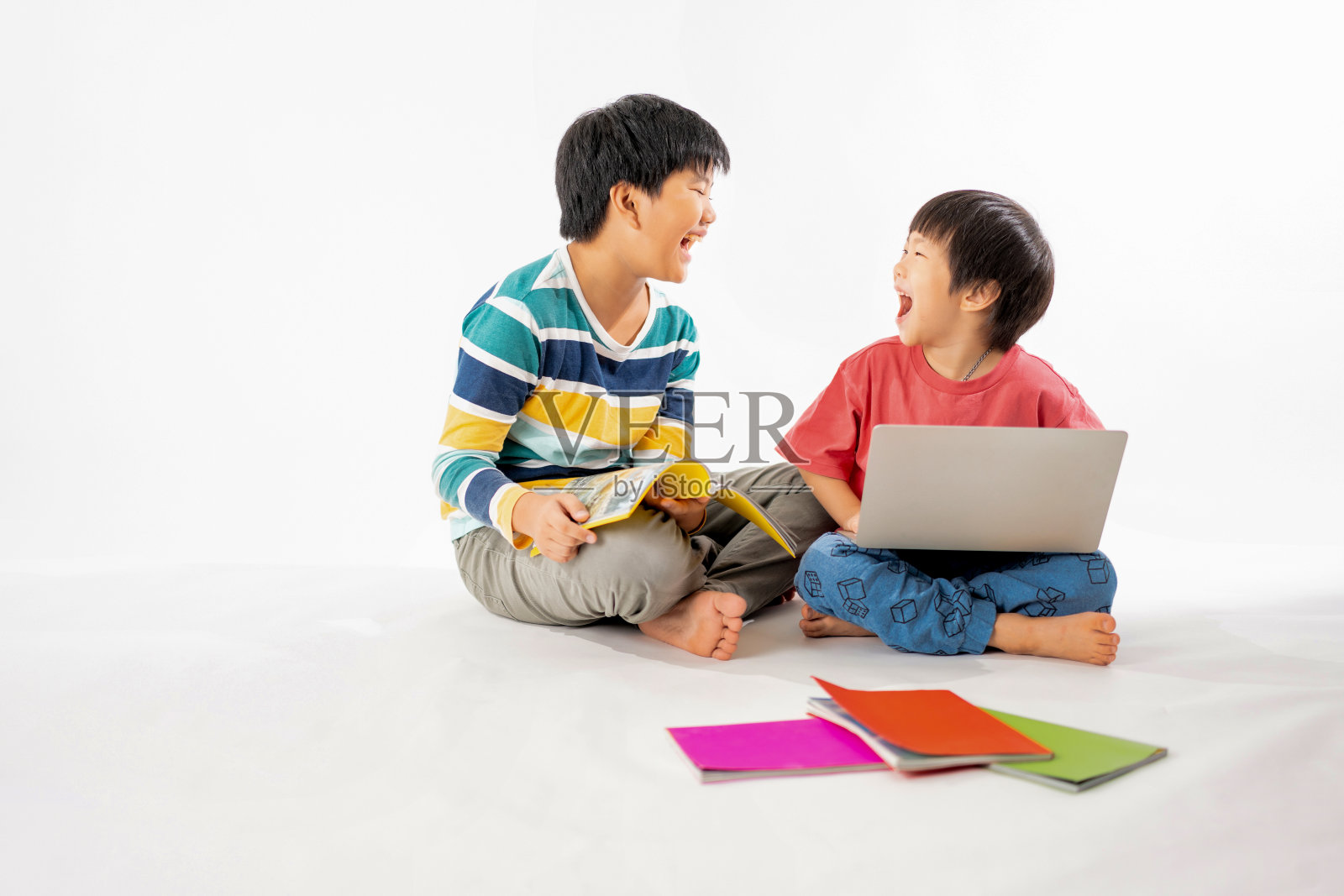快乐亚洲男孩的肖像，兄弟在地板上笔记本电脑和书本孤立的白色背景，教育和学习的技术概念照片摄影图片