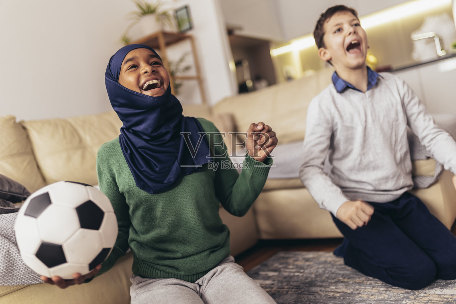 女孩和她的白人朋友在家里看足球比赛照片摄影图片