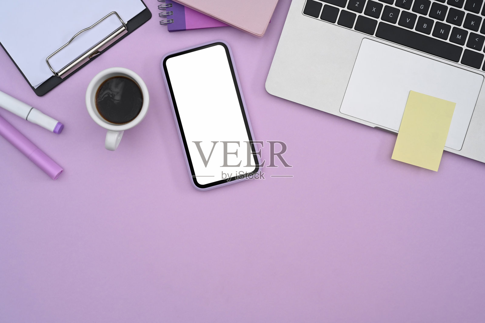 女性的工作场所与智能手机，笔记本电脑和文具在紫色的背景。照片摄影图片