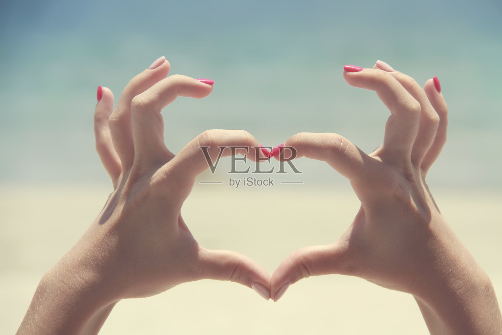 在沙滩背景上制作心形手势。美丽的手与复制空间。情人节爱的概念照片摄影图片