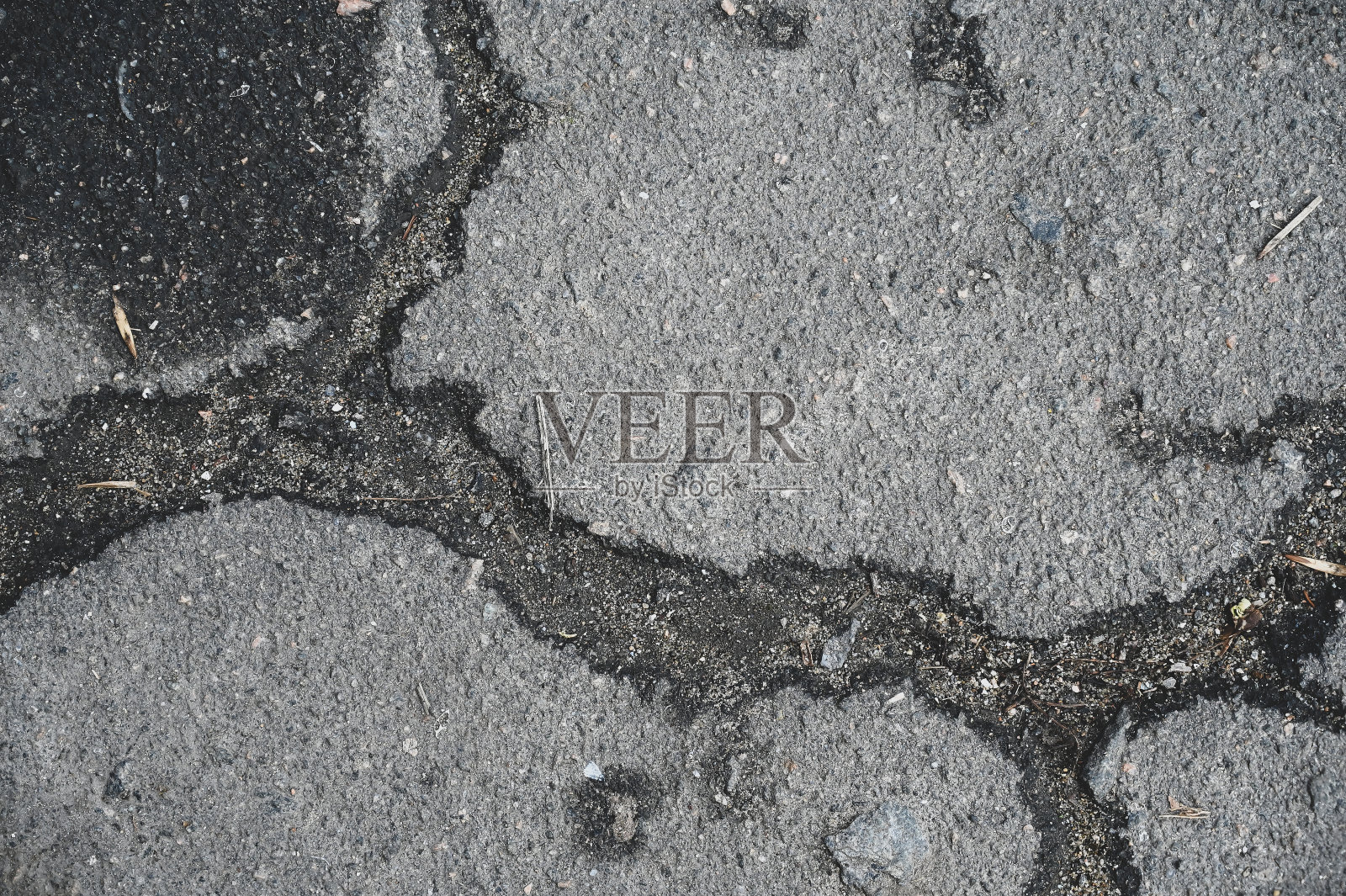 旧的、磨损的、有裂缝的、开裂的沥青。受损路面的纹理。照片摄影图片