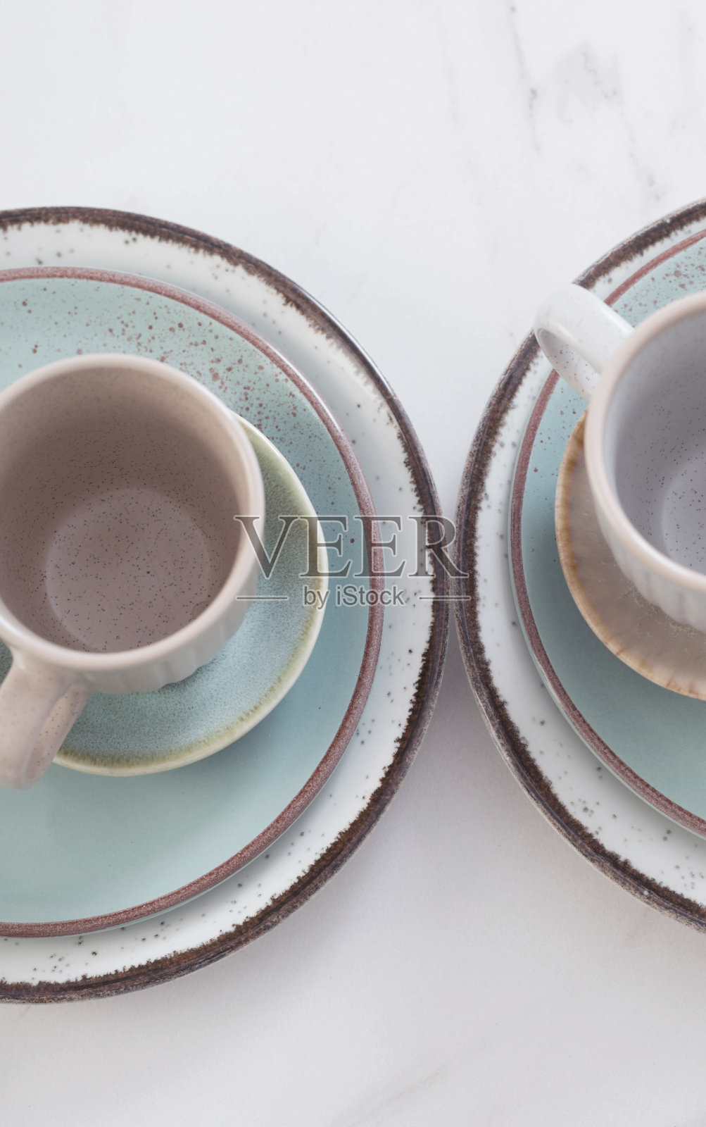 两个陶瓷杯子和盘子在白色大理石桌子上照片摄影图片