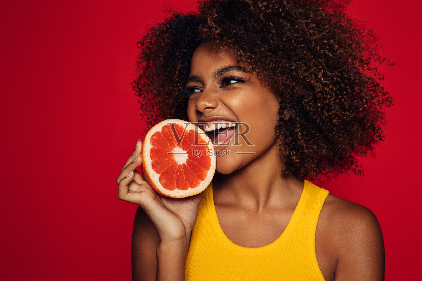 美丽的非洲发型女人拿着一个葡萄柚照片摄影图片