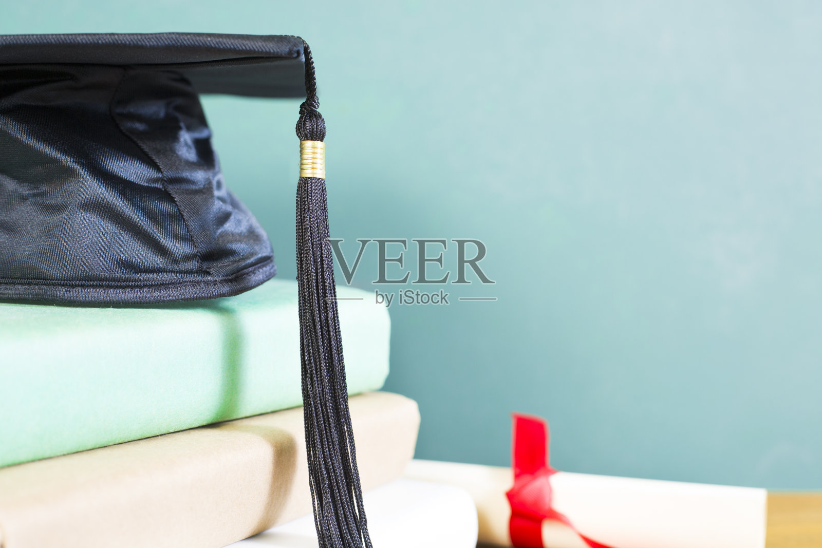 粉笔板背景与学位帽，教科书和文凭在一个抛光的木桌。绝佳的复印空间。照片摄影图片