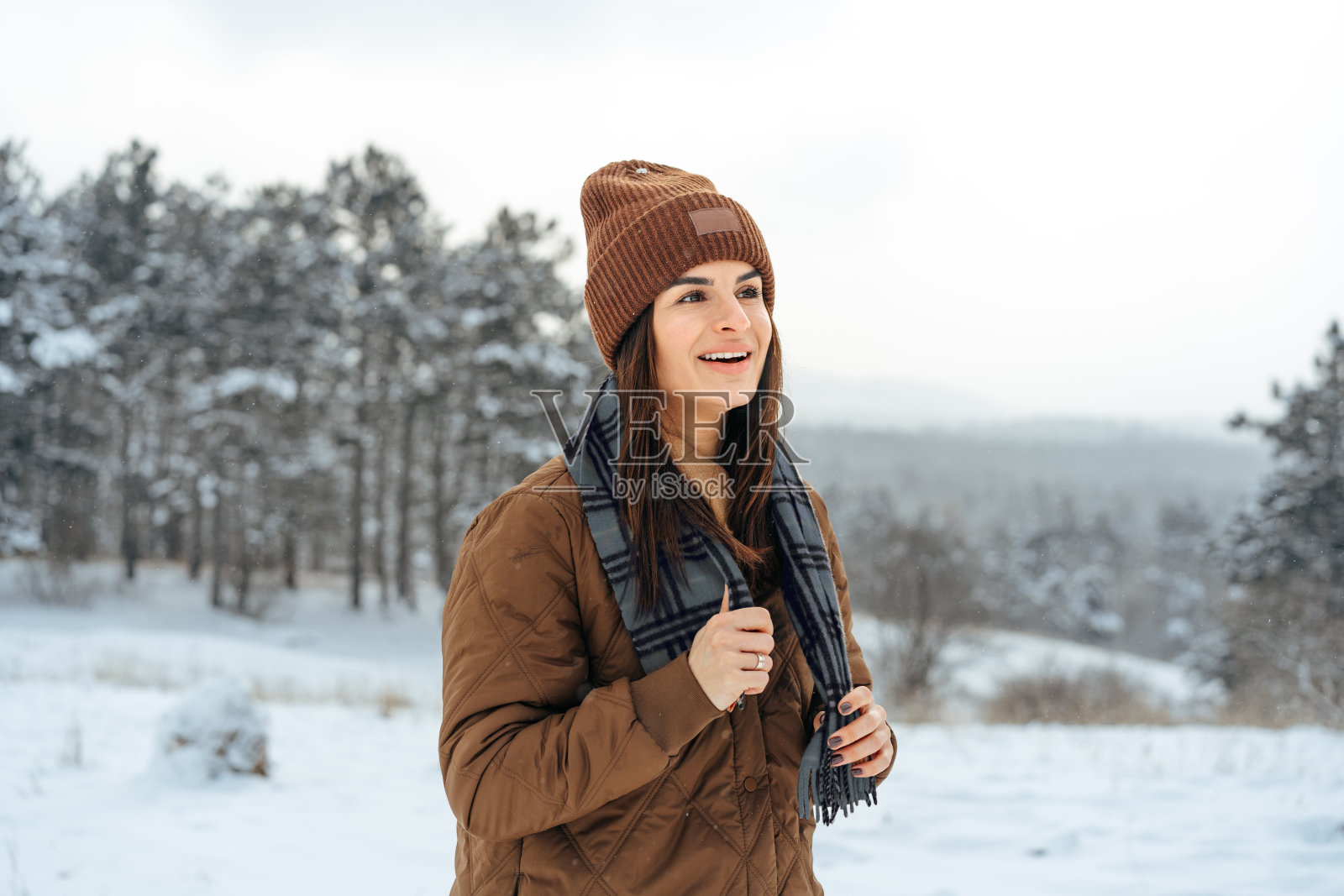 女人穿着冬天暖和的夹克走在雪的冬天的森林照片摄影图片