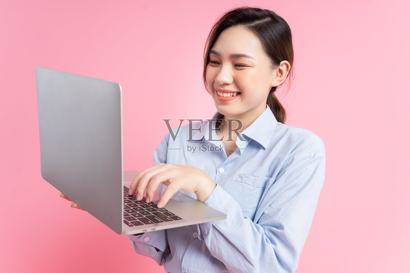 年轻的亚洲女商人在粉红色背景下拿着笔记本电脑的图像照片摄影图片