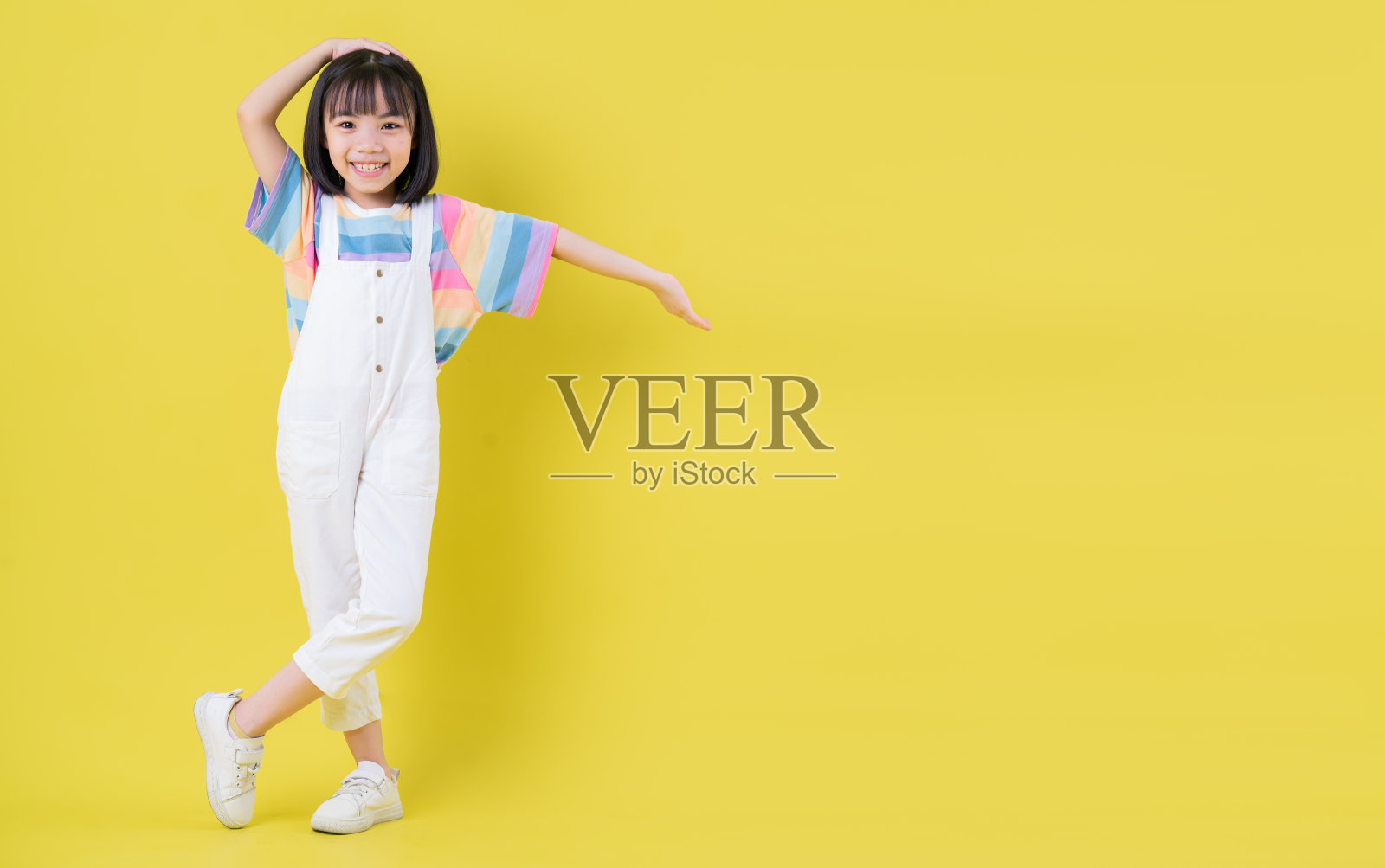 在黄色背景上摆姿势的亚洲孩子的全长图像照片摄影图片
