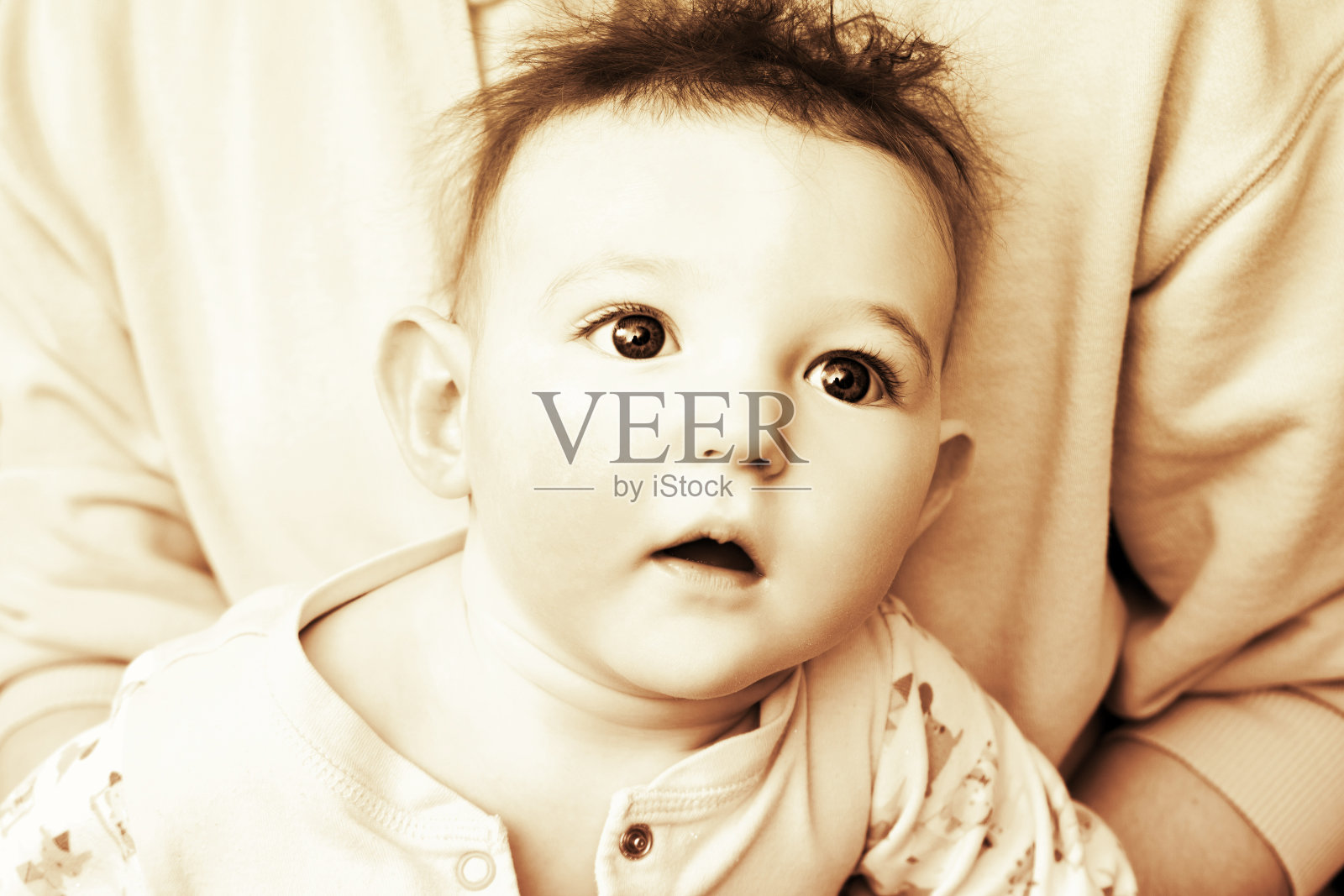 惊讶的婴儿，蓝色的大眼睛，蓬乱的头发，棕褐色。一个头发凌乱的受惊的孩子的肖像，黑白相间照片摄影图片