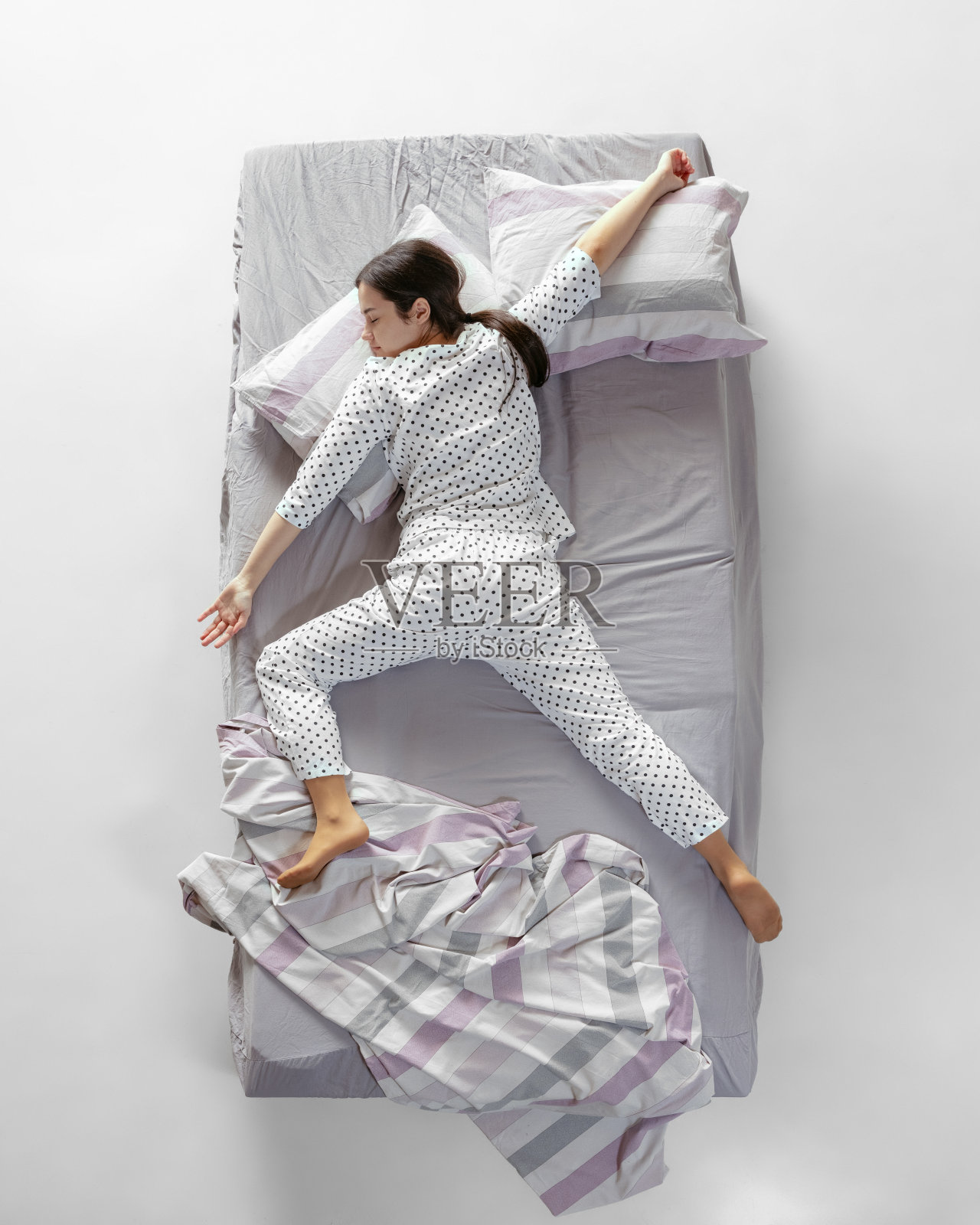 鸟瞰图，睡在白色睡衣的年轻女孩躺在灰色的大床上。健康理念，家居内饰，放松时间，家庭，梦想照片摄影图片