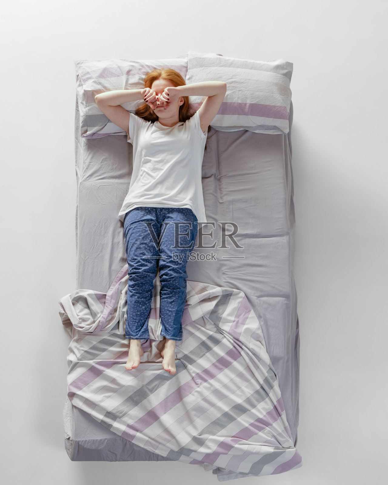 鸟瞰图，一头红发的年轻女孩穿着棉质家居服躺在巨大的灰色床上睡觉。健康理念，家居内饰，放松时间，家庭，梦想照片摄影图片