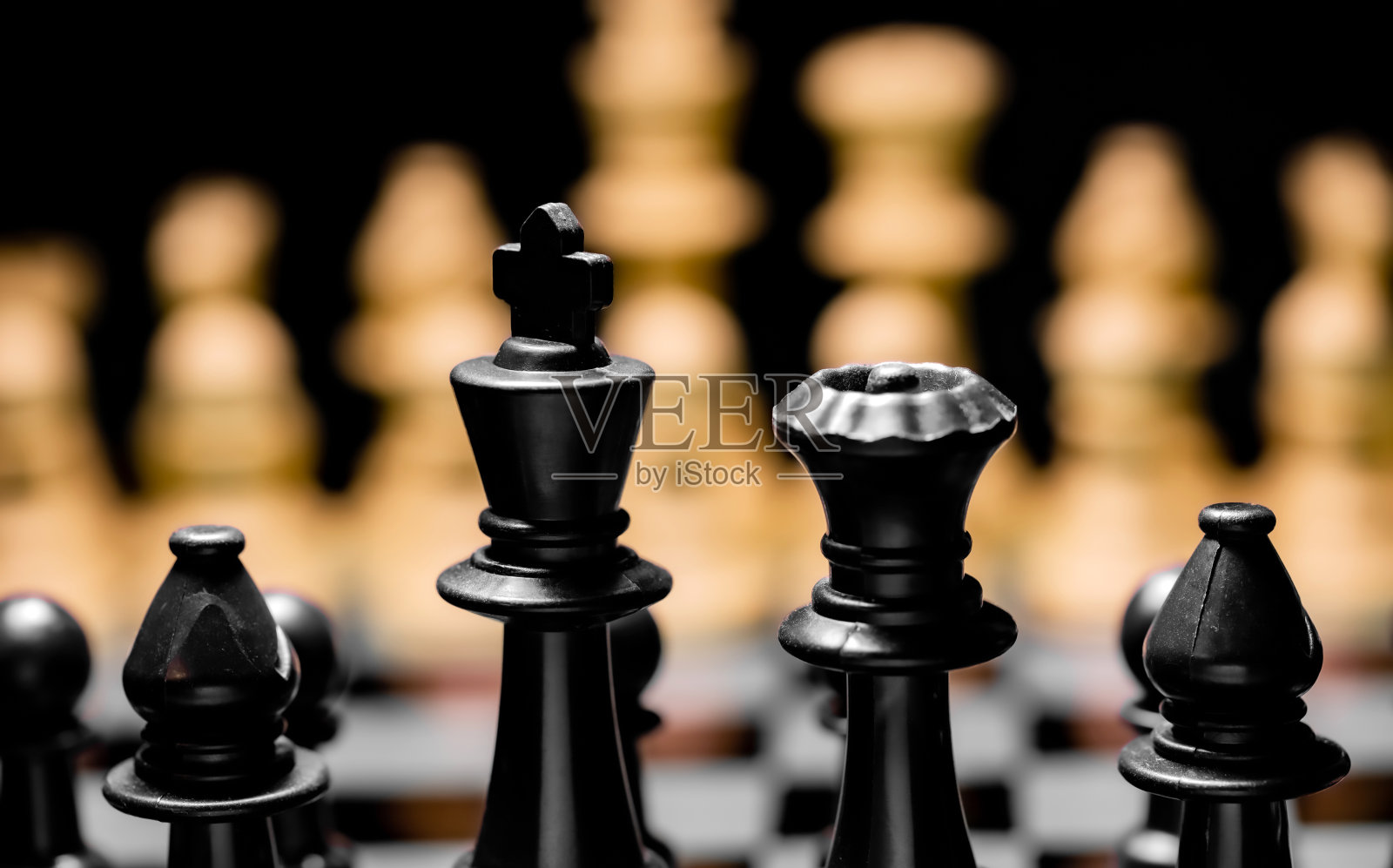 近的国际象棋棋子在一个反射镜板表面与黑色背景照片摄影图片