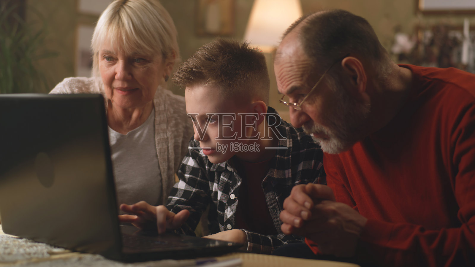 十几岁的孙子在笔记本电脑上玩游戏照片摄影图片