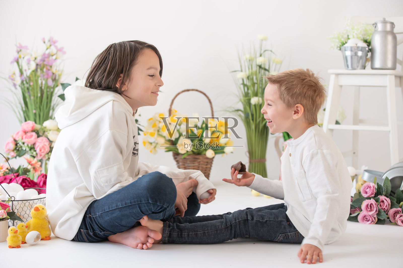 可爱时尚的蹒跚学步的孩子和哥哥，穿着白衬衫的男孩，在复活节装饰上玩彩蛋和巧克力兔子照片摄影图片