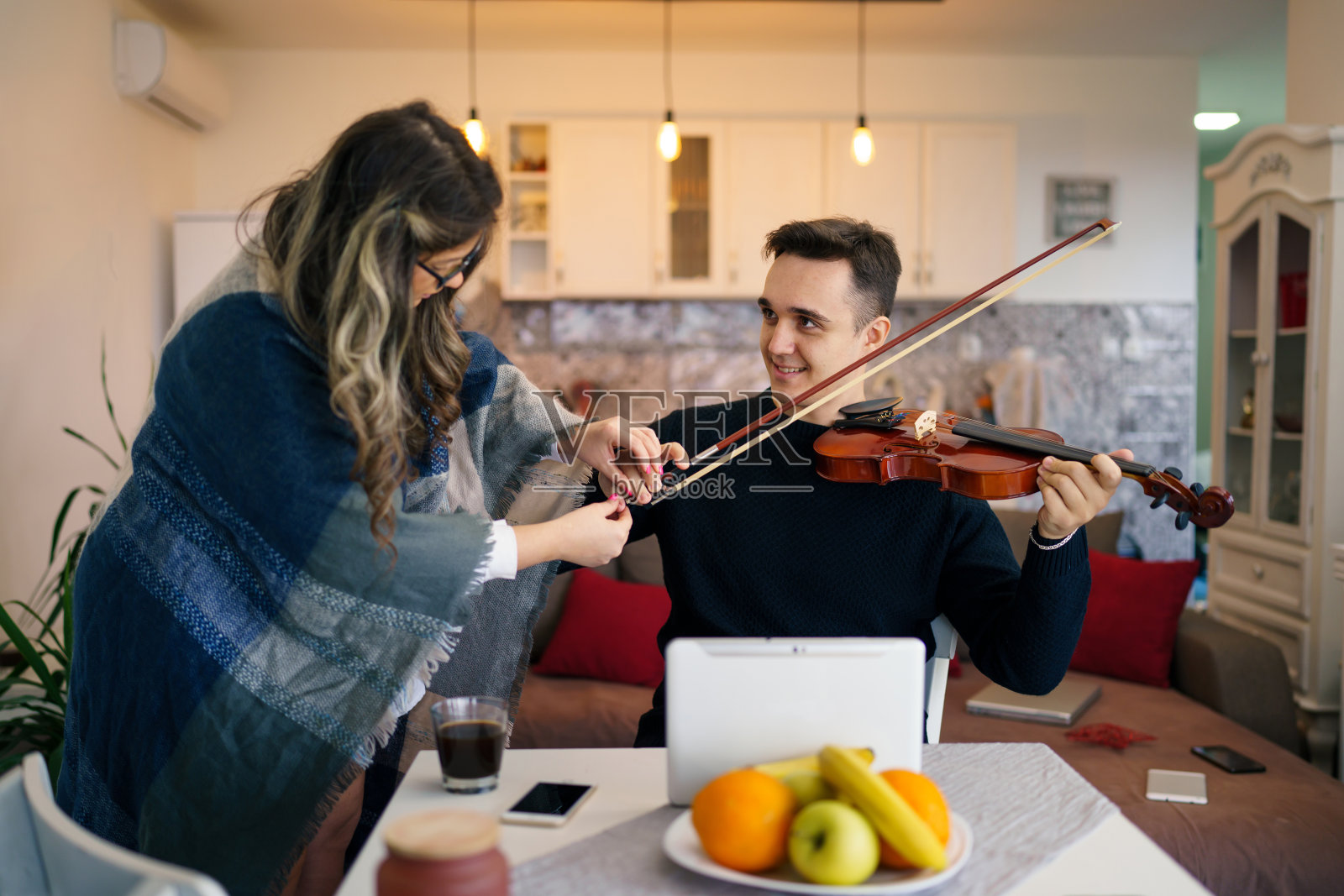 年轻的成年白人男子学生学习拉小提琴，在他的教授，女女导师的帮助下，教他如何提高技能，在家里解释课程真人私课的概念照片摄影图片