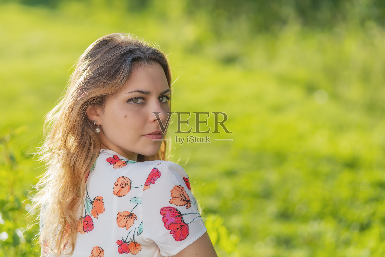 年轻女子正回头看着户外的照相机。照片摄影图片