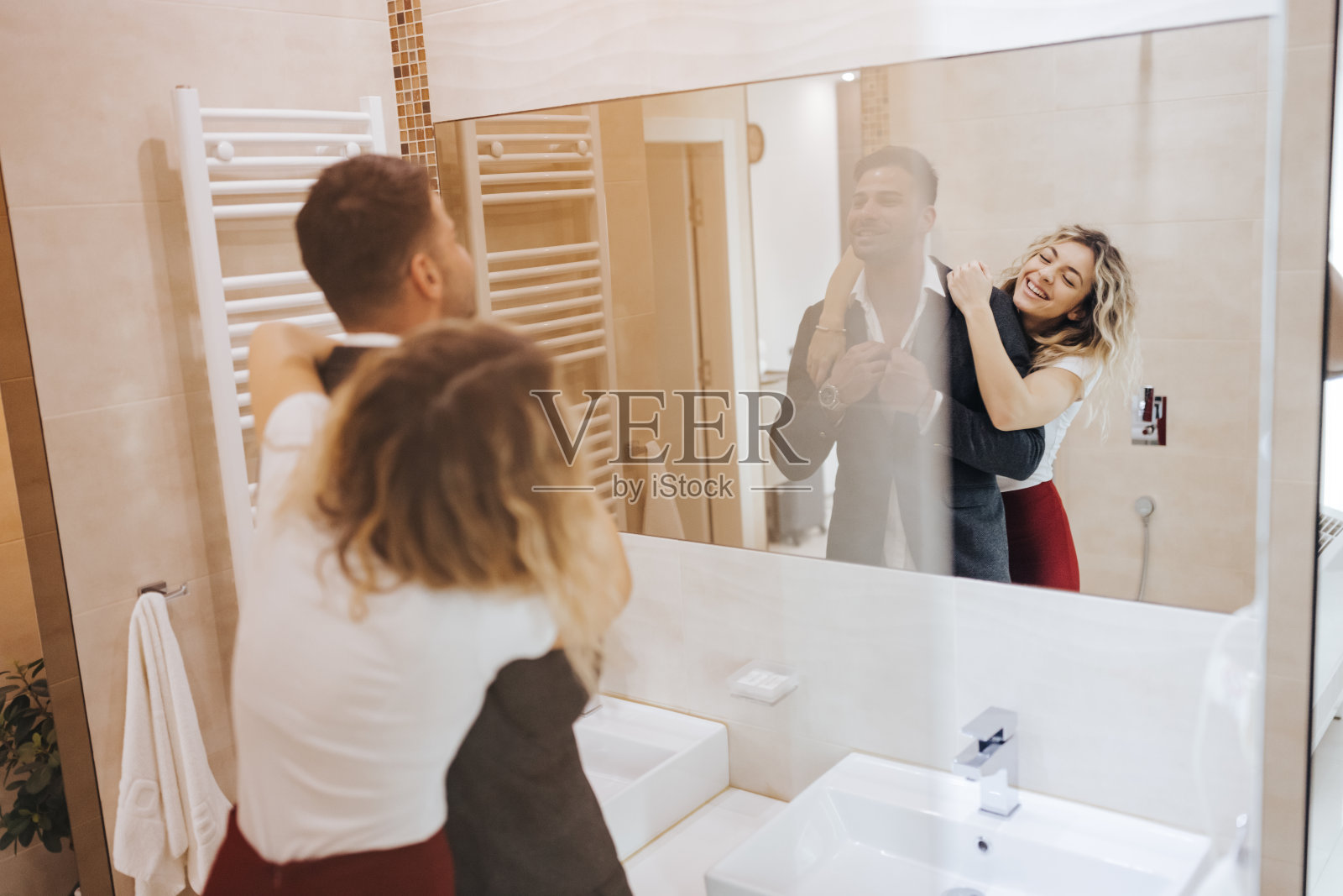 美丽的年轻夫妇看着浴室的镜子，而准备出去照片摄影图片
