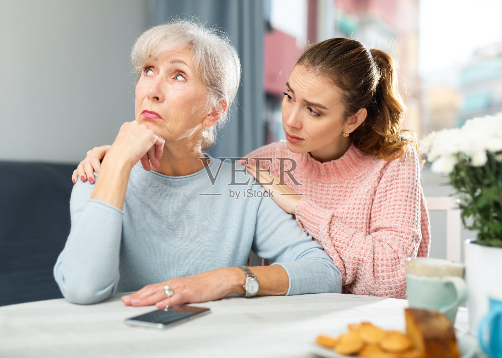 成年女儿在餐桌旁安慰争吵后心烦的母亲照片摄影图片