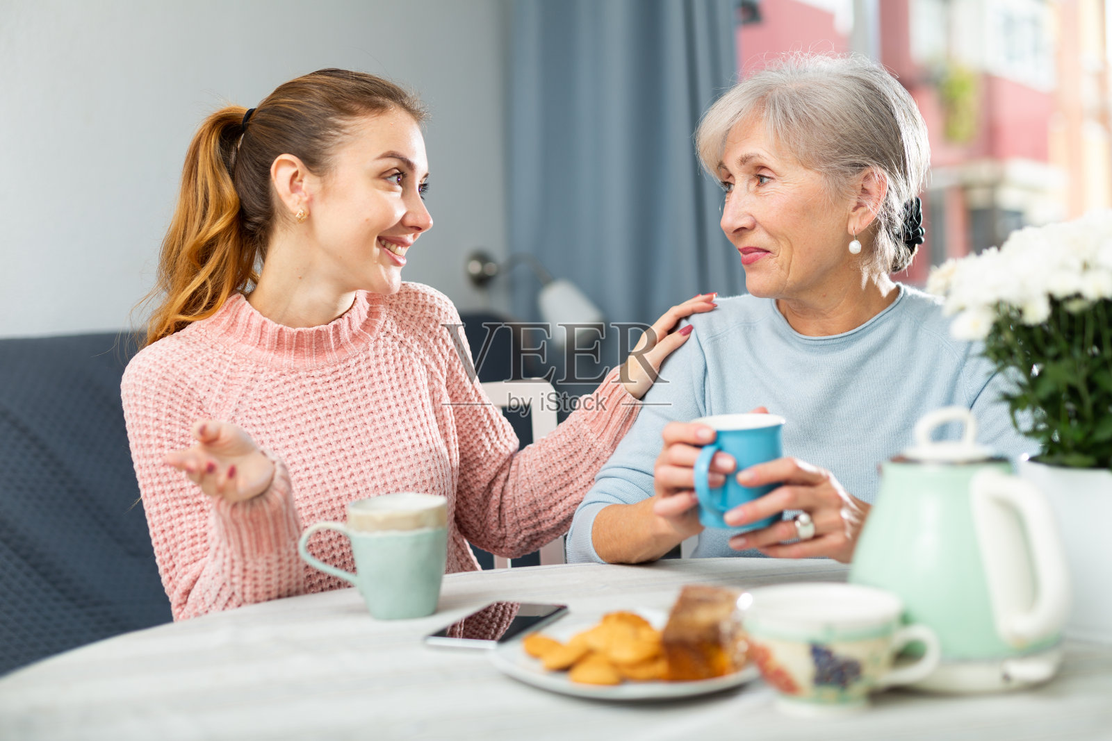 年迈的母亲和成年的女儿在家里喝茶聊天照片摄影图片