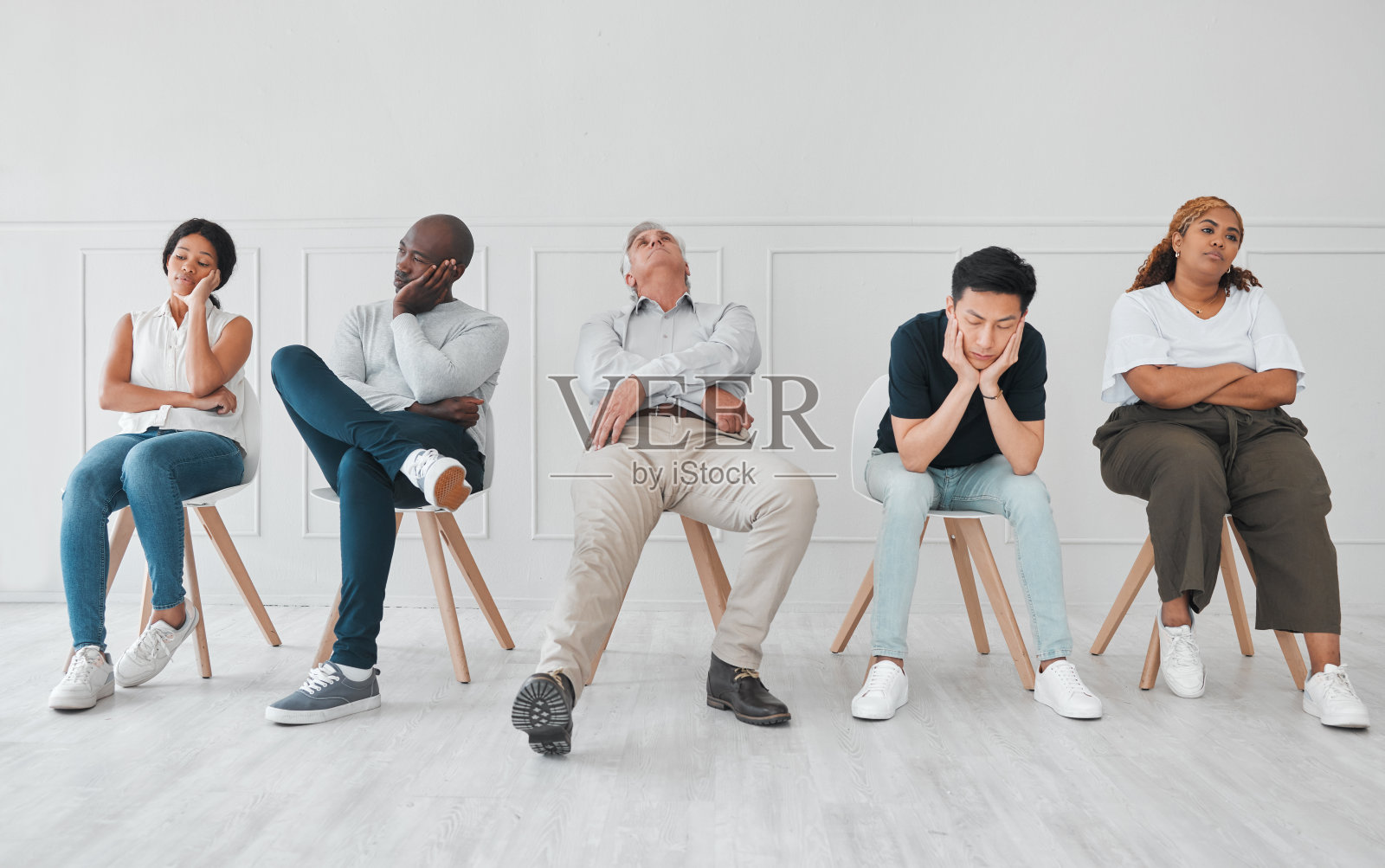 这张照片拍摄的是一群看起来很无聊的人，他们在白色的背景下排排坐着照片摄影图片