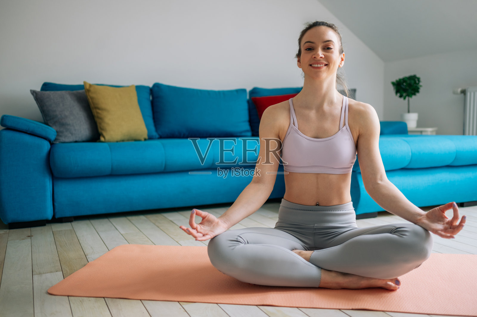 一个女人以莲花瑜伽的姿势坐在家里的健身垫上照片摄影图片