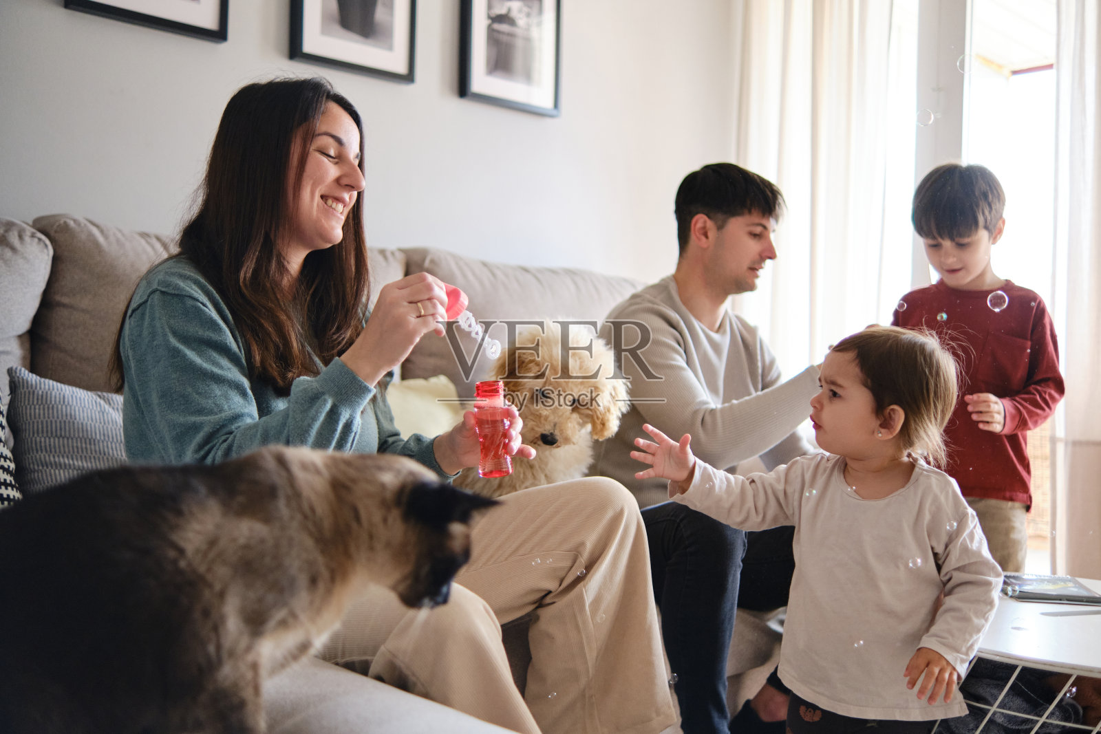 快乐的一家人在家里吹肥皂泡玩得很开心。照片摄影图片