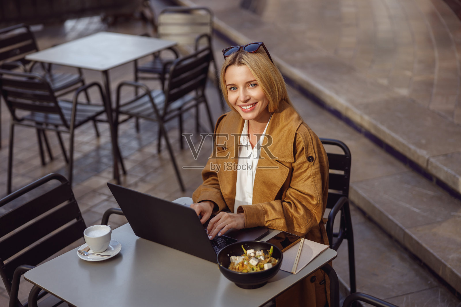 美丽的女人在笔记本电脑上打字，而坐在桌子外面照片摄影图片