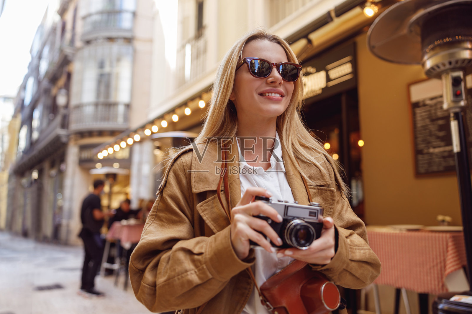 漂亮的雌猫带着相机走在街上照片摄影图片
