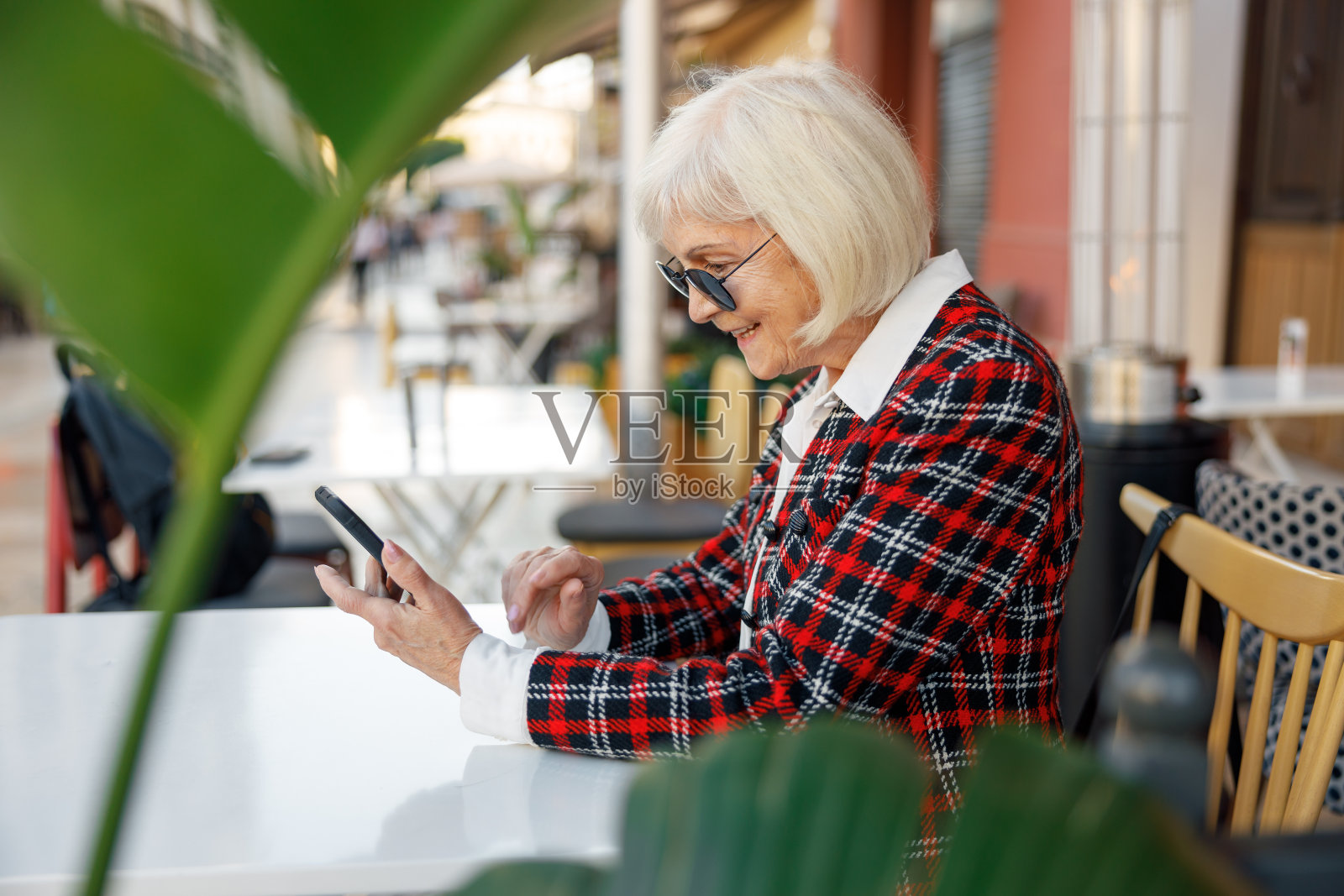 老妇人在路边咖啡馆用手机照片摄影图片