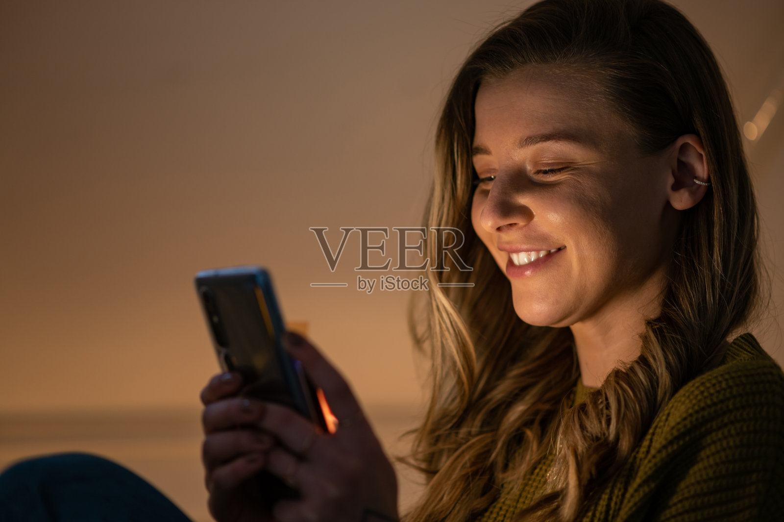 坐在沙发上玩智能手机的女人照片摄影图片