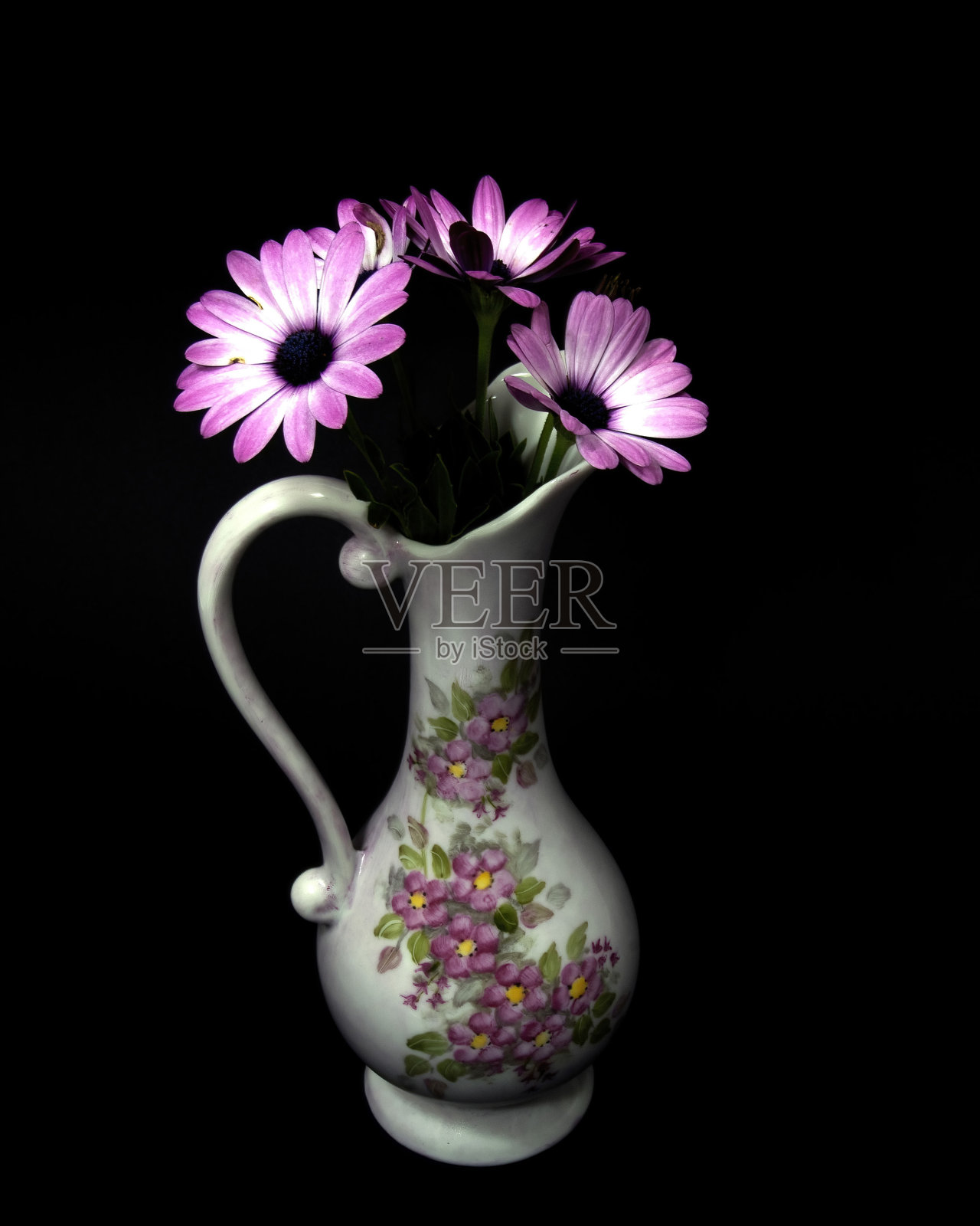 粉红色和白色的非洲雏菊花在一个装饰花瓶上孤立的黑色背景。照片摄影图片