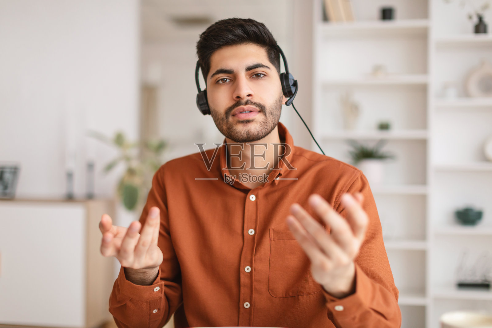 阿拉伯男子使用笔记本电脑，头戴耳机坐在桌前照片摄影图片