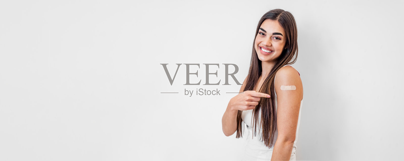 高兴的白人女孩的肖像，指着，戴着创可贴。照片摄影图片