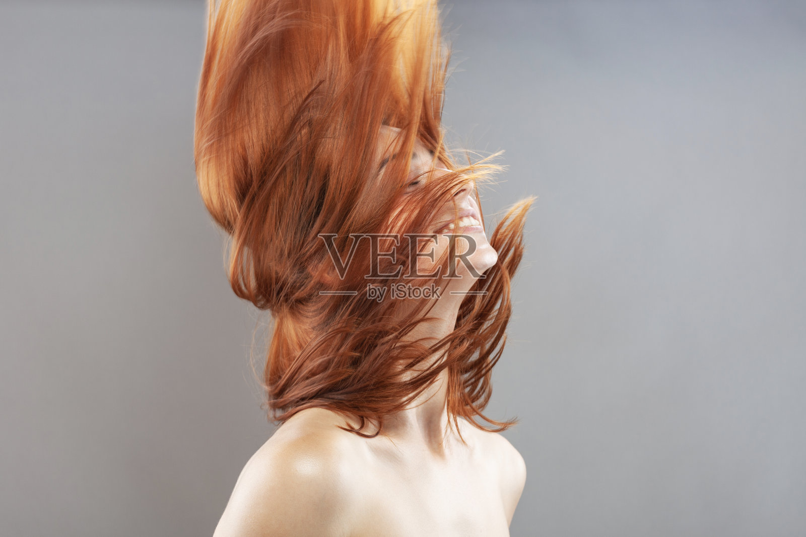 美丽的深色烧伤橙色风发女孩微笑。工作室肖像与快乐的脸表情对灰色背景…照片摄影图片