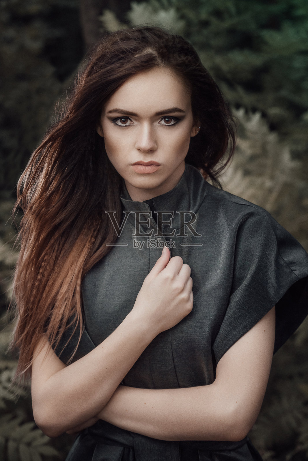 森林里的女性户外肖像。黑暗中的童话气氛。时尚人士穿着漂亮的棕色外套。自然界中的林地生物。照片摄影图片