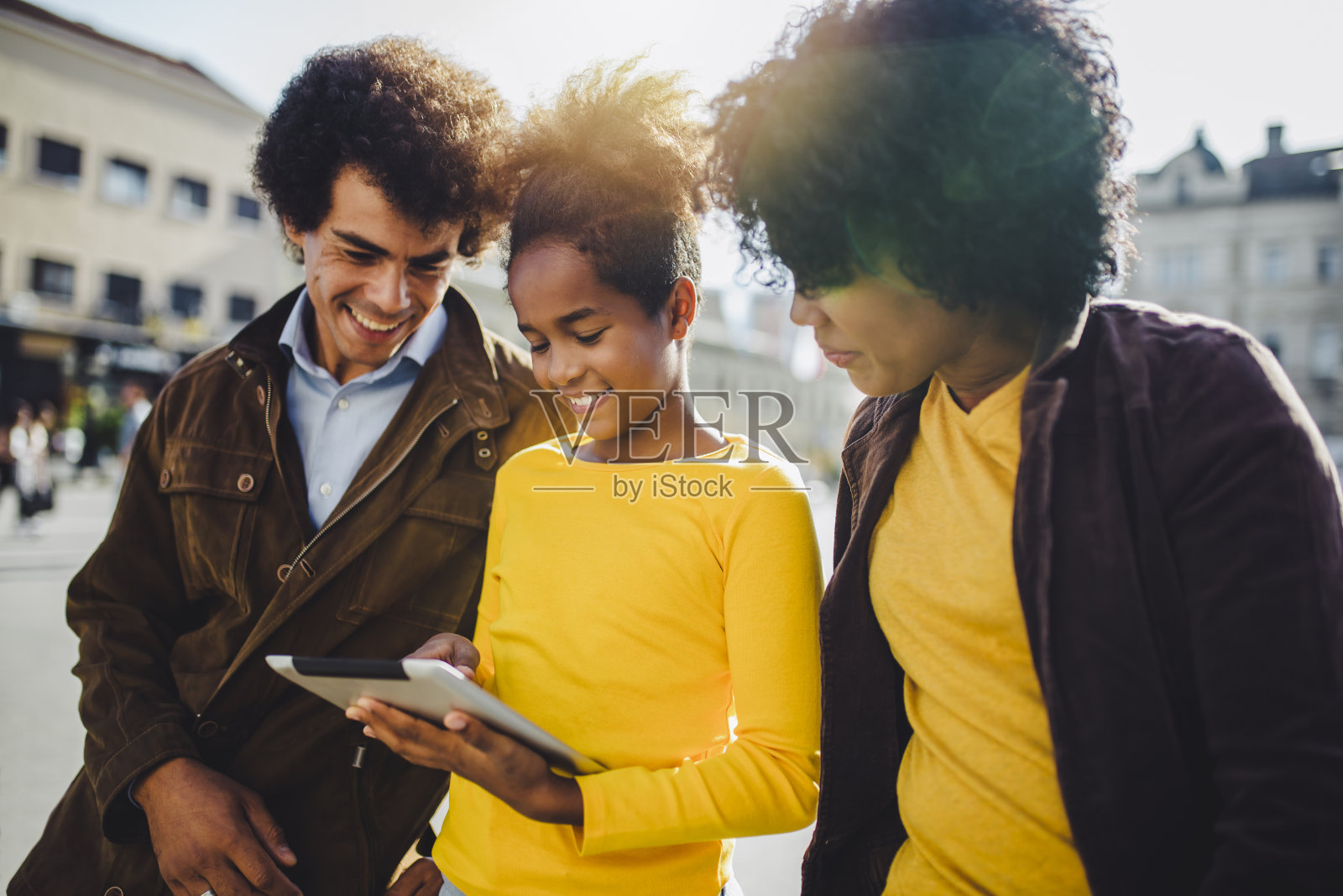 一家人坐在长椅上，放松地使用小工具，浏览互联网。照片摄影图片