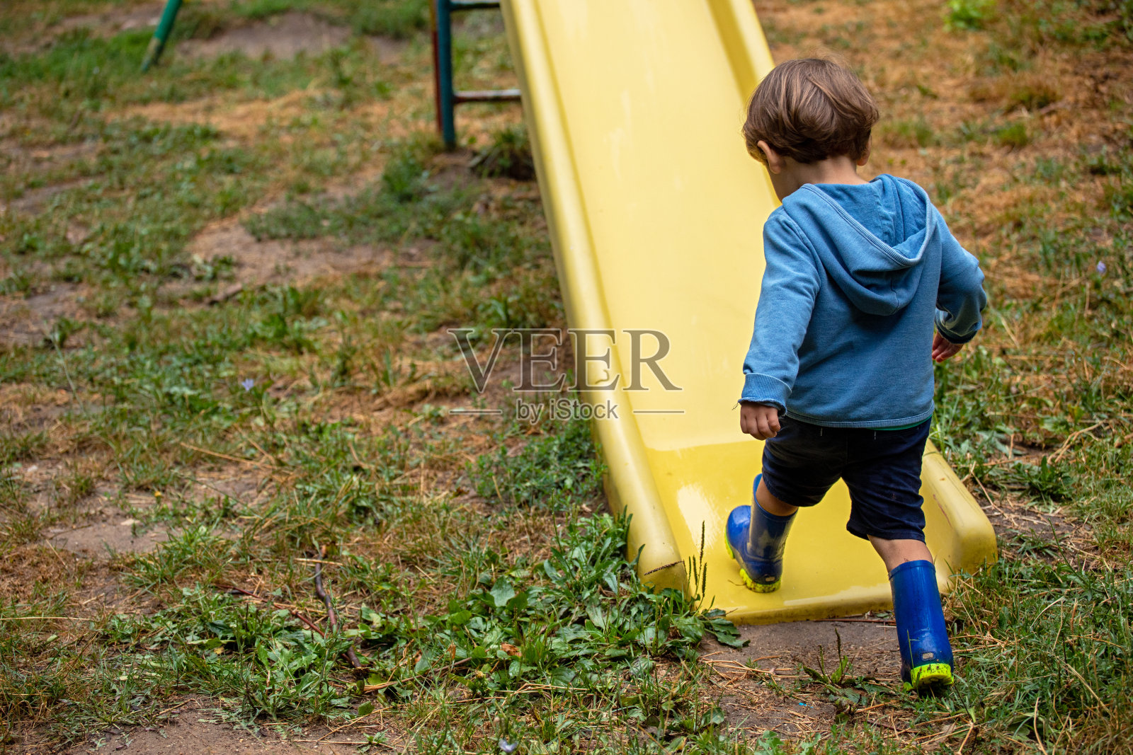 一个小孩在雨天的操场上玩耍照片摄影图片