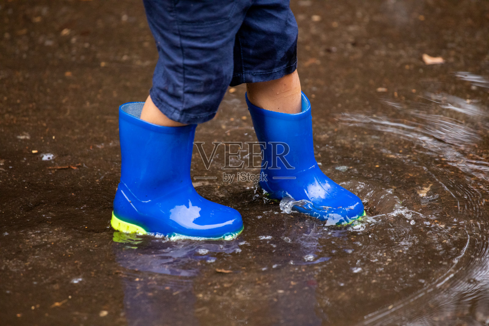 一个小孩在雨天走在水里照片摄影图片