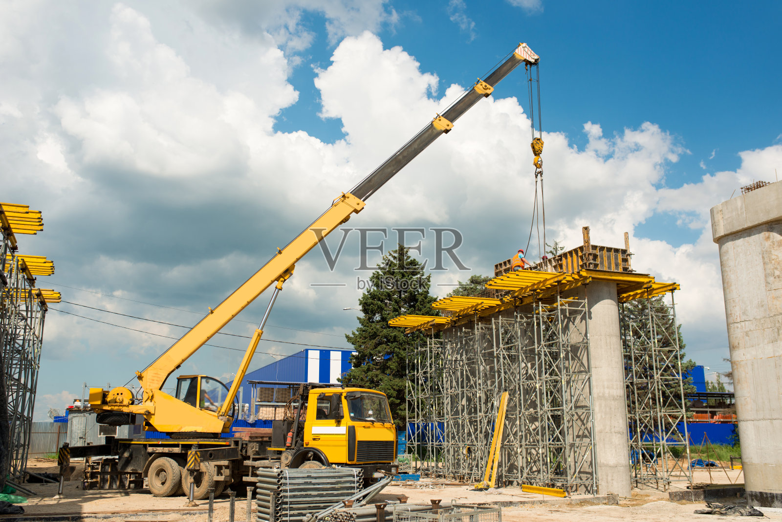 在天空的背景下，起重机在建筑工地吊起货物照片摄影图片