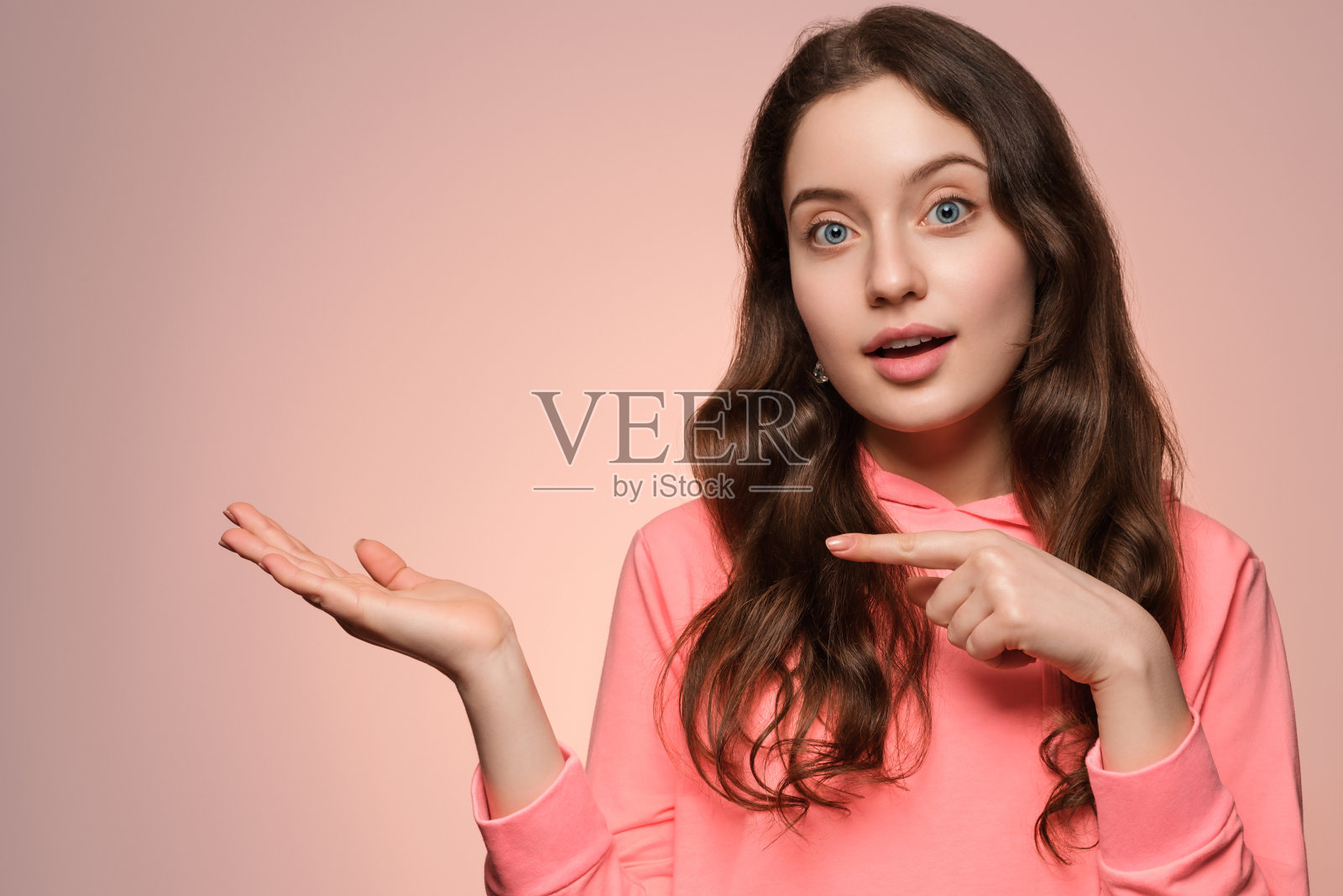 一个长着长发和蓝眼睛的年轻女孩用手指着两边。照片摄影图片