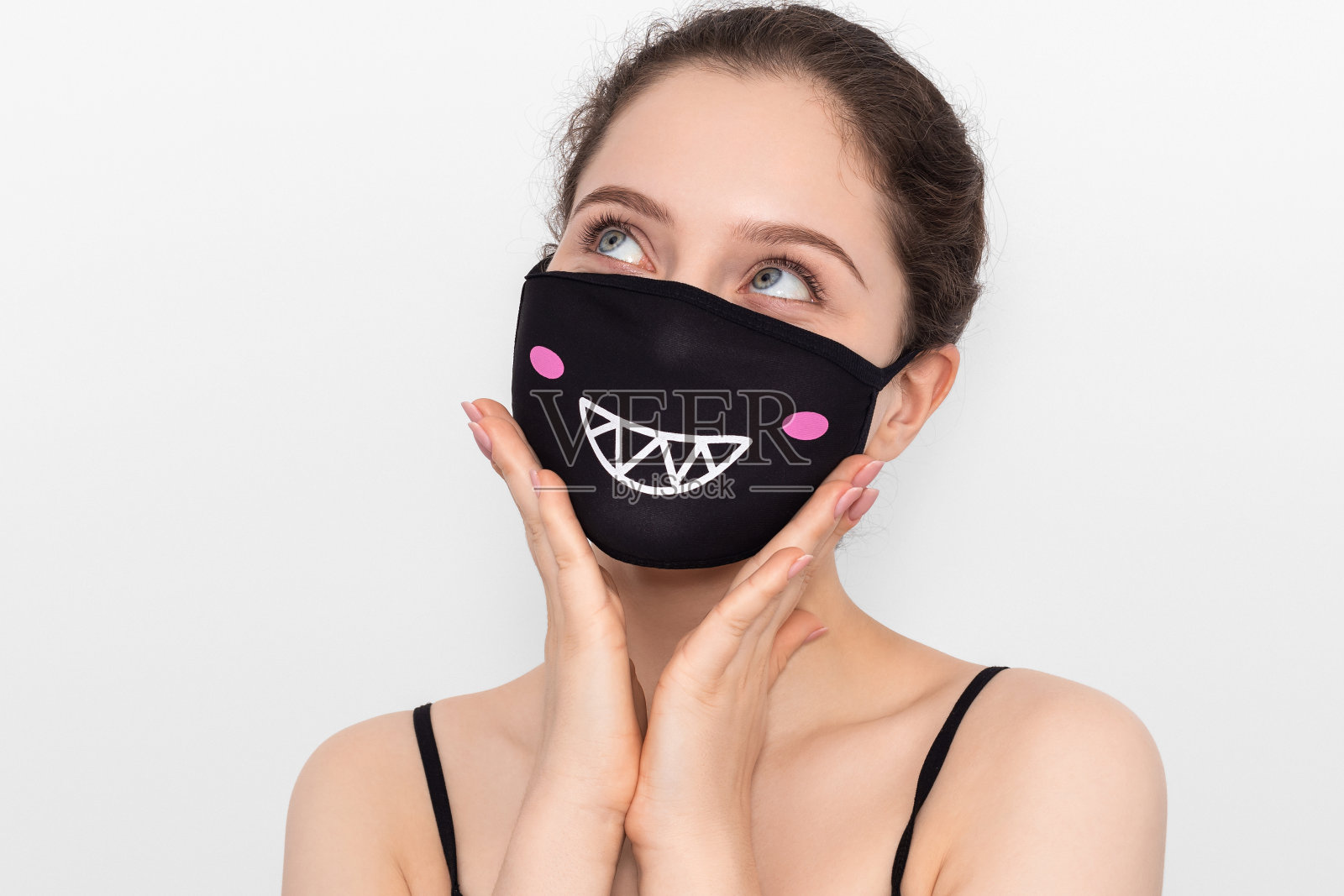 年轻女孩戴着印有图案的面具，身穿灰色背景的黑色t恤。有着蓝色大眼睛的女孩。照片摄影图片