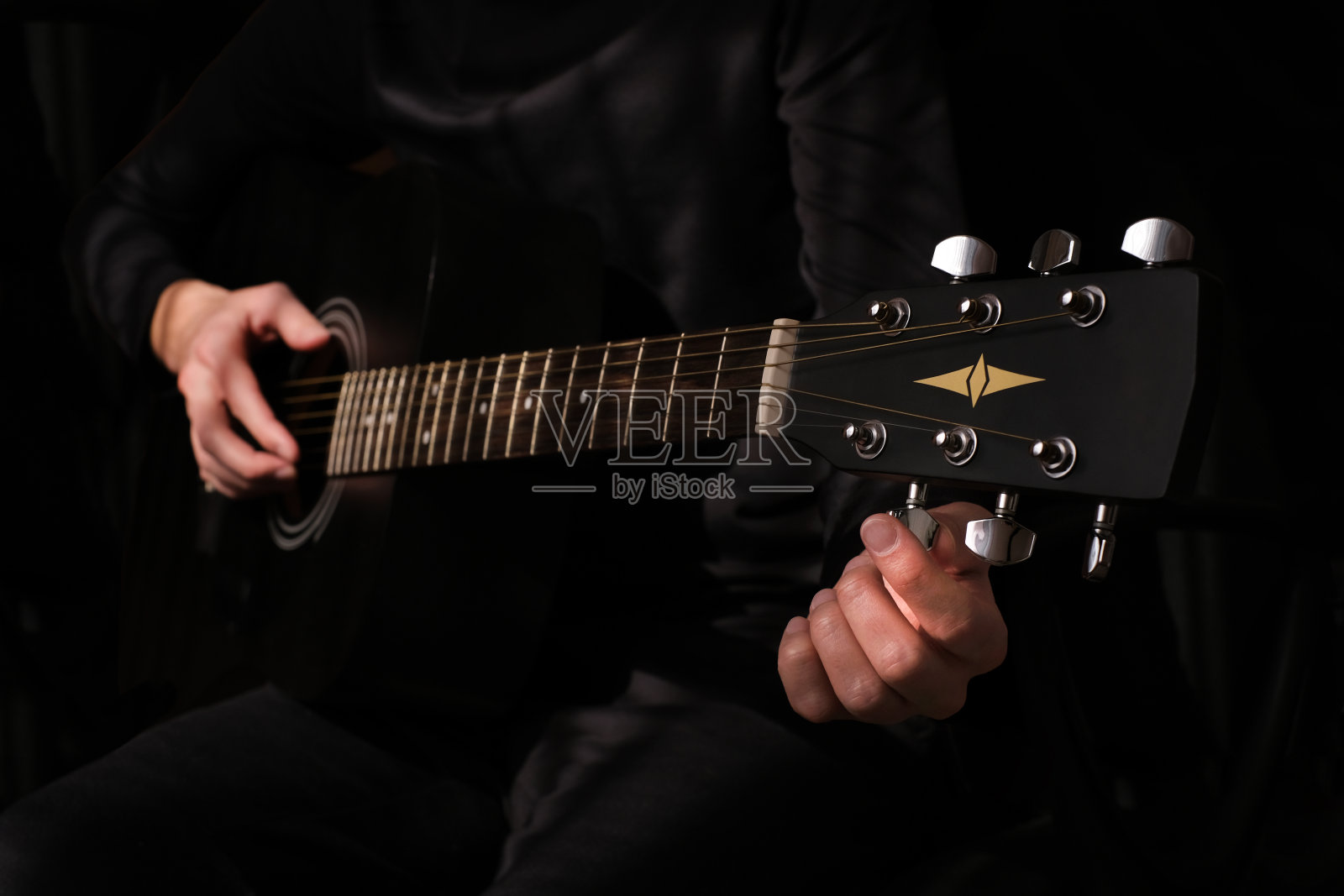 男音乐家在给吉他调弦照片摄影图片