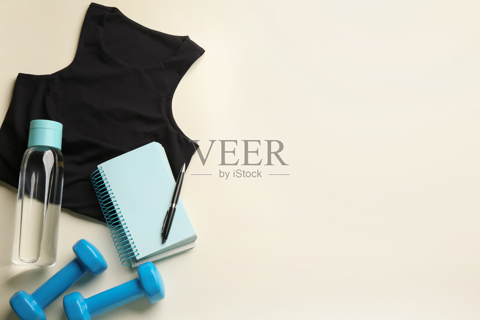 平铺构图与运动服和笔记本在光的背景，文字的空间。健身房的锻炼计划照片摄影图片