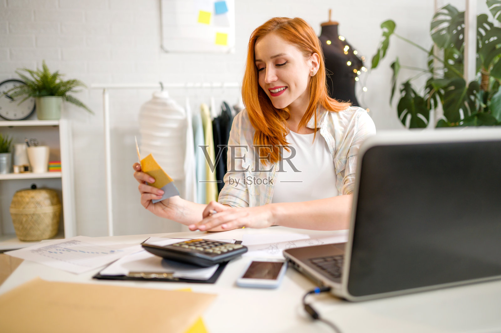 微笑的年轻女企业家在她的时装设计工作室工作照片摄影图片