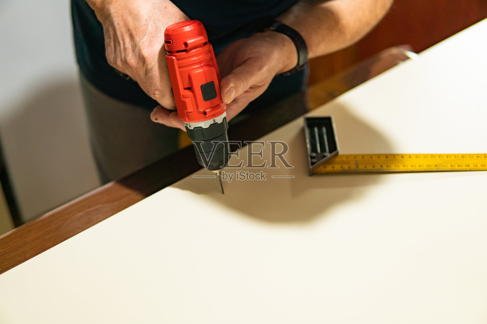 一个人钻一块木板(胶合板)来做他在家做的家具。在家DIY项目。照片摄影图片