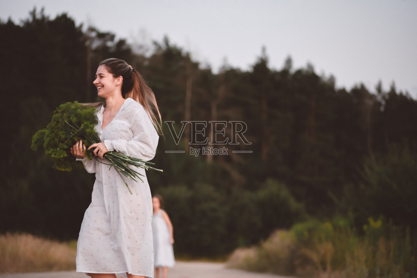 一个穿裙子的女孩走在森林里。照片摄影图片