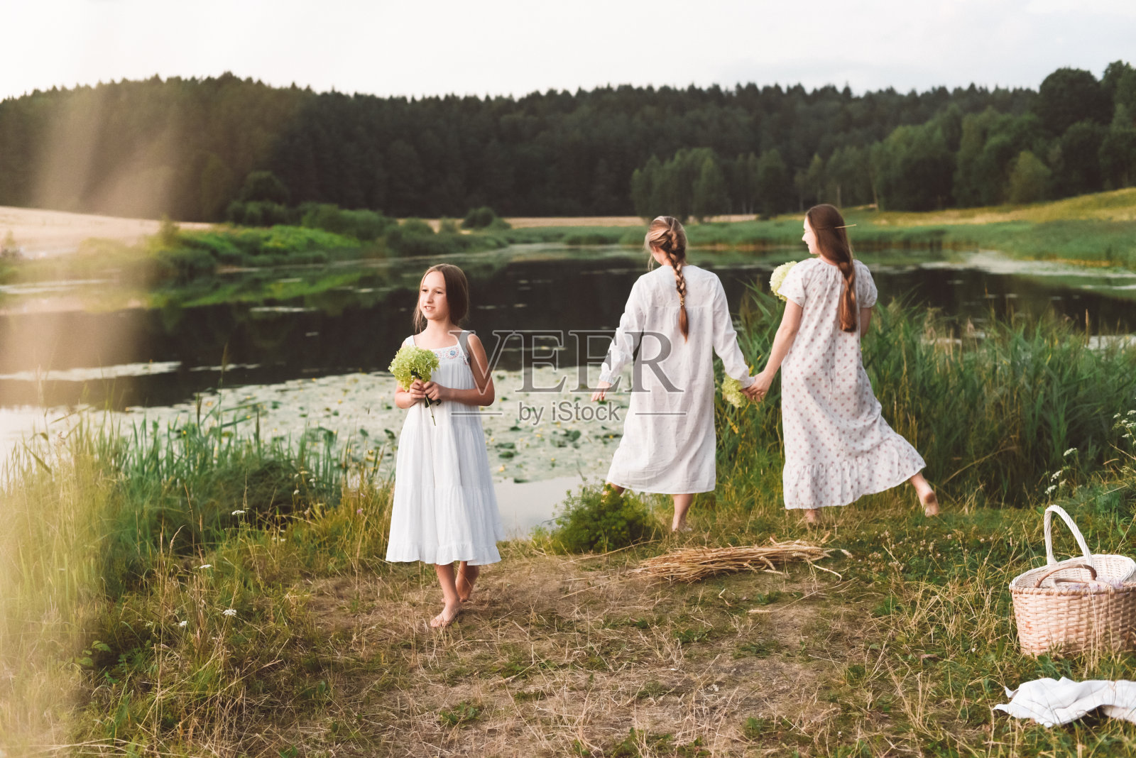 穿着白色睡裙的女孩在湖边摆姿势，温暖的夏日照片摄影图片