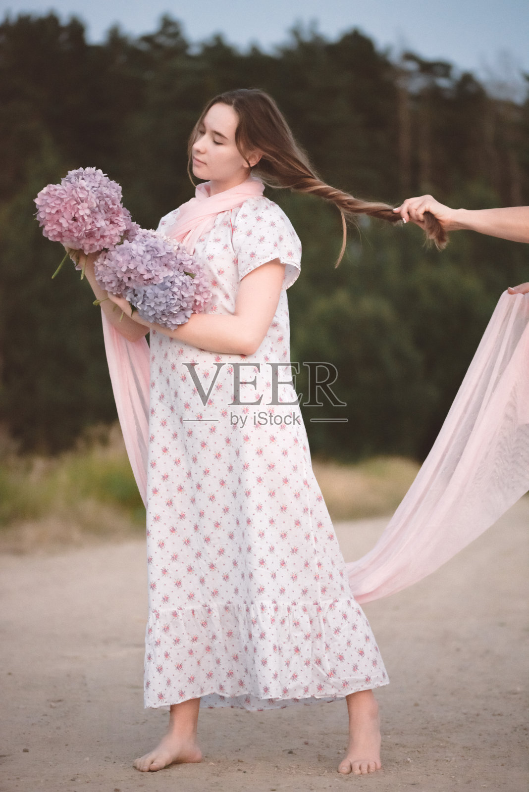 森林边的女孩手里捧着花。照片摄影图片